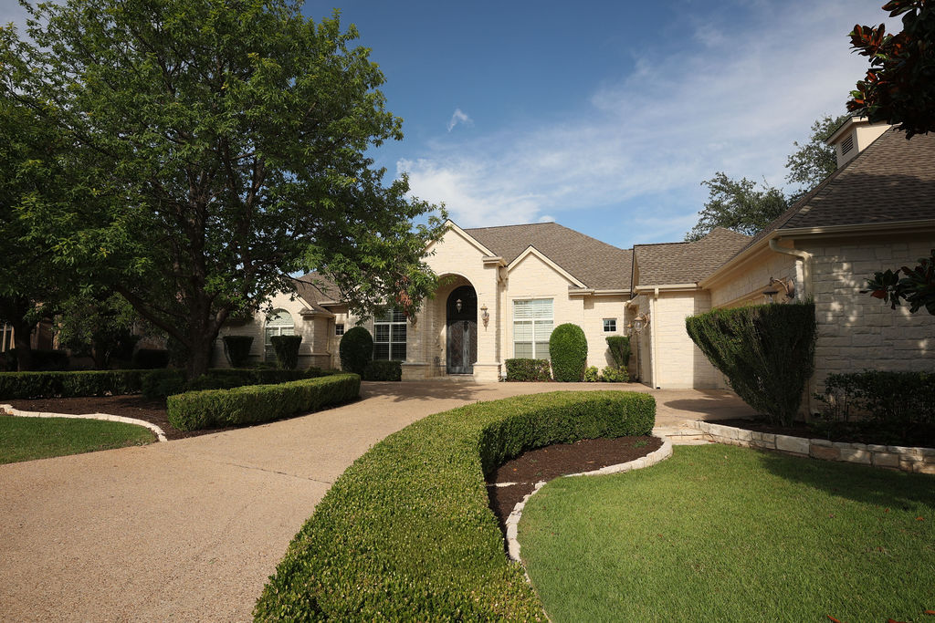 200 Stardust Lane Georgetown, TX 78633 - Photo 1 of 1 A graceful driveway leads to a custom home featuring stone construction and a well-manicured landscape.