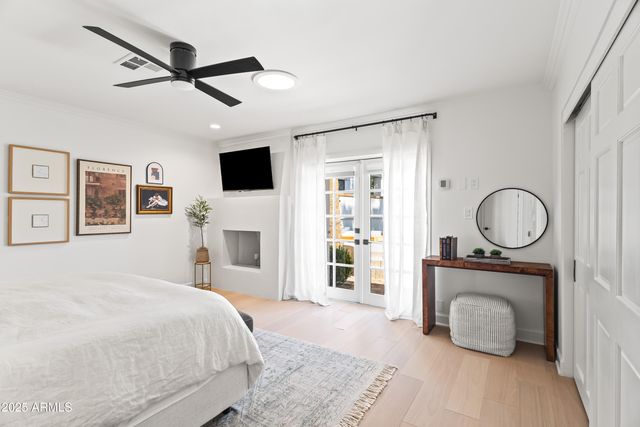 a bedroom with a large bed a flat tv screen and a fireplace