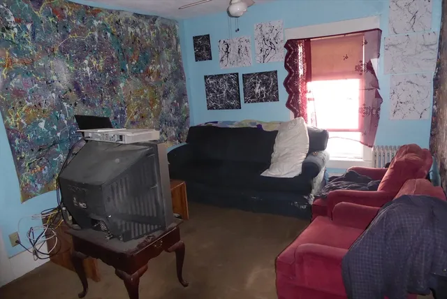 a living room with furniture and a refrigerator