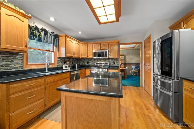 a kitchen with stainless steel appliances granite countertop a refrigerator a sink dishwasher a stove with wooden cabinets and floor