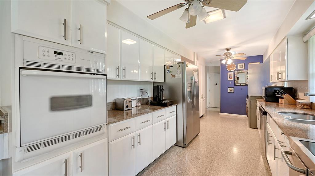 3012 Desoto Road Sarasota, FL 34234 - Photo 30 of 78 a kitchen with stainless steel appliances kitchen island granite countertop a refrigerator a stove a sink dishwasher and white cabinets with wooden floor
