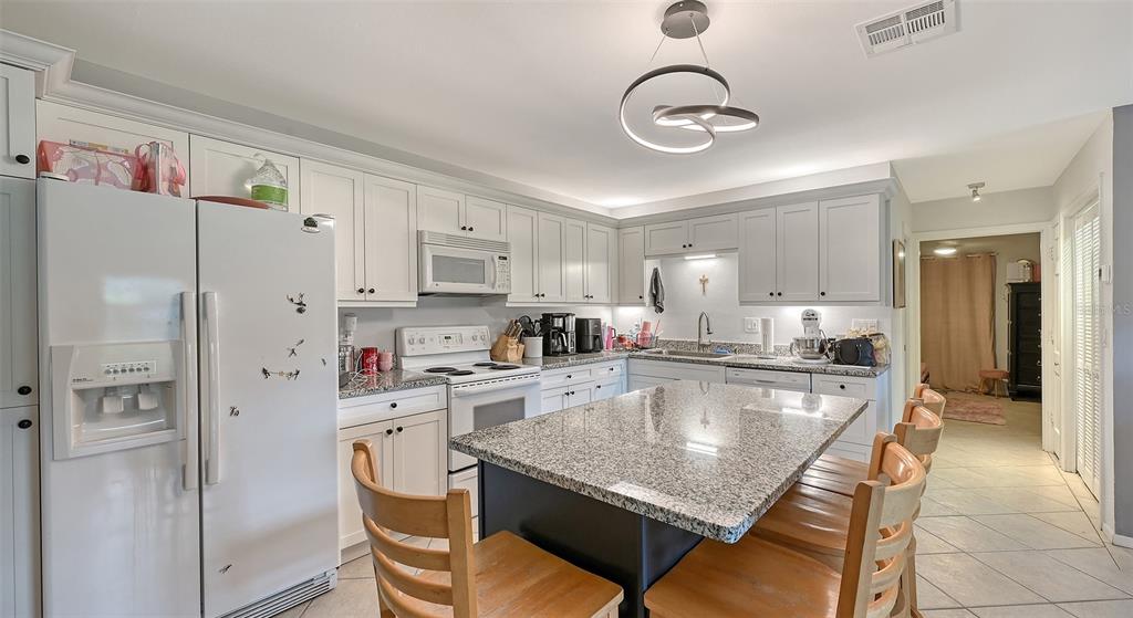 3012 Desoto Road Sarasota, FL 34234 - Photo 65 of 78 a kitchen with stainless steel appliances granite countertop a refrigerator a sink dishwasher a stove and white cabinets with wooden floor