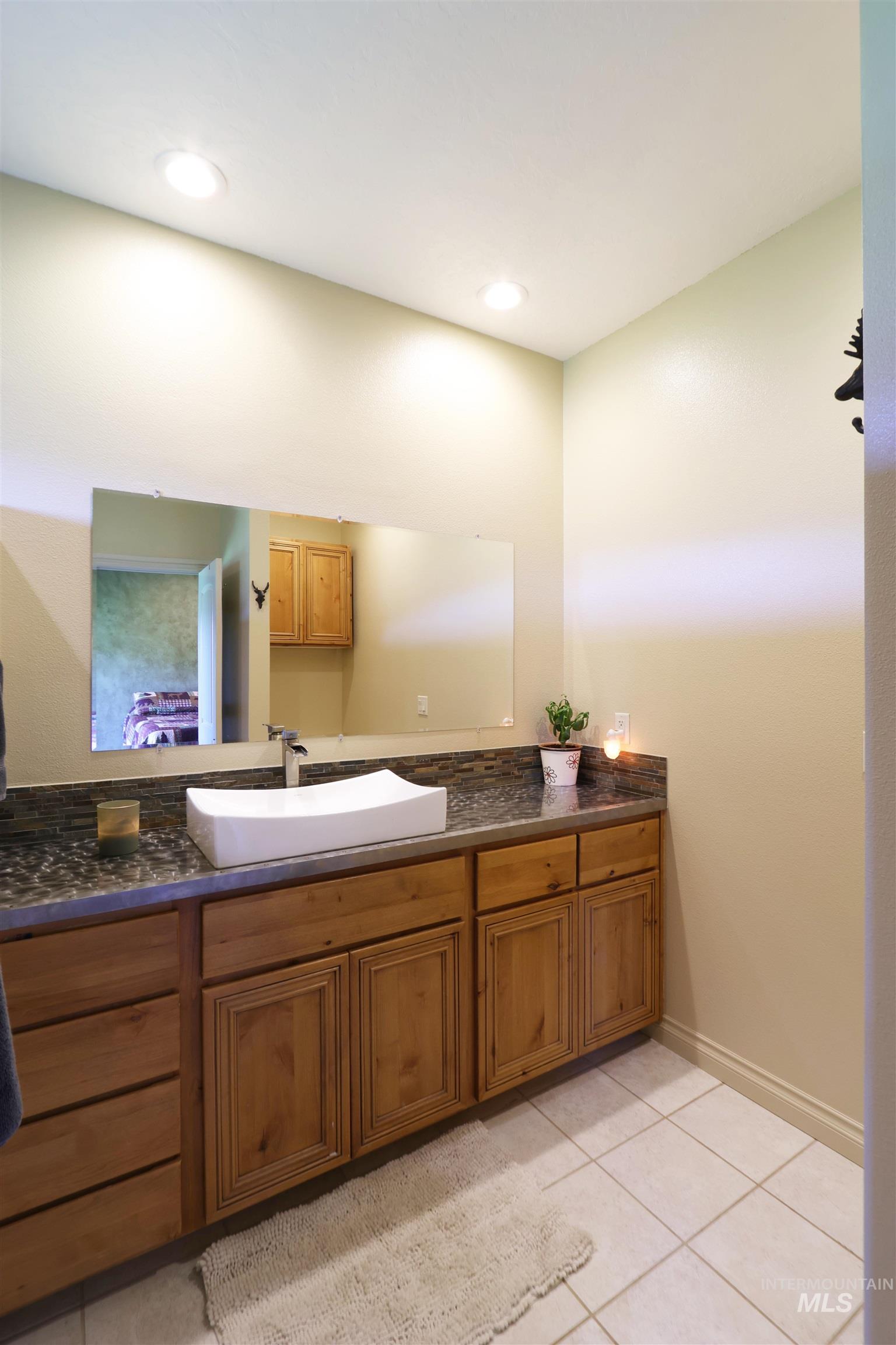 2278 Golf Lane Council, ID 83612 - Photo 13 of 31 Bathroom vanity featuring a vessel sink, dark countertop, and wood cabinetry