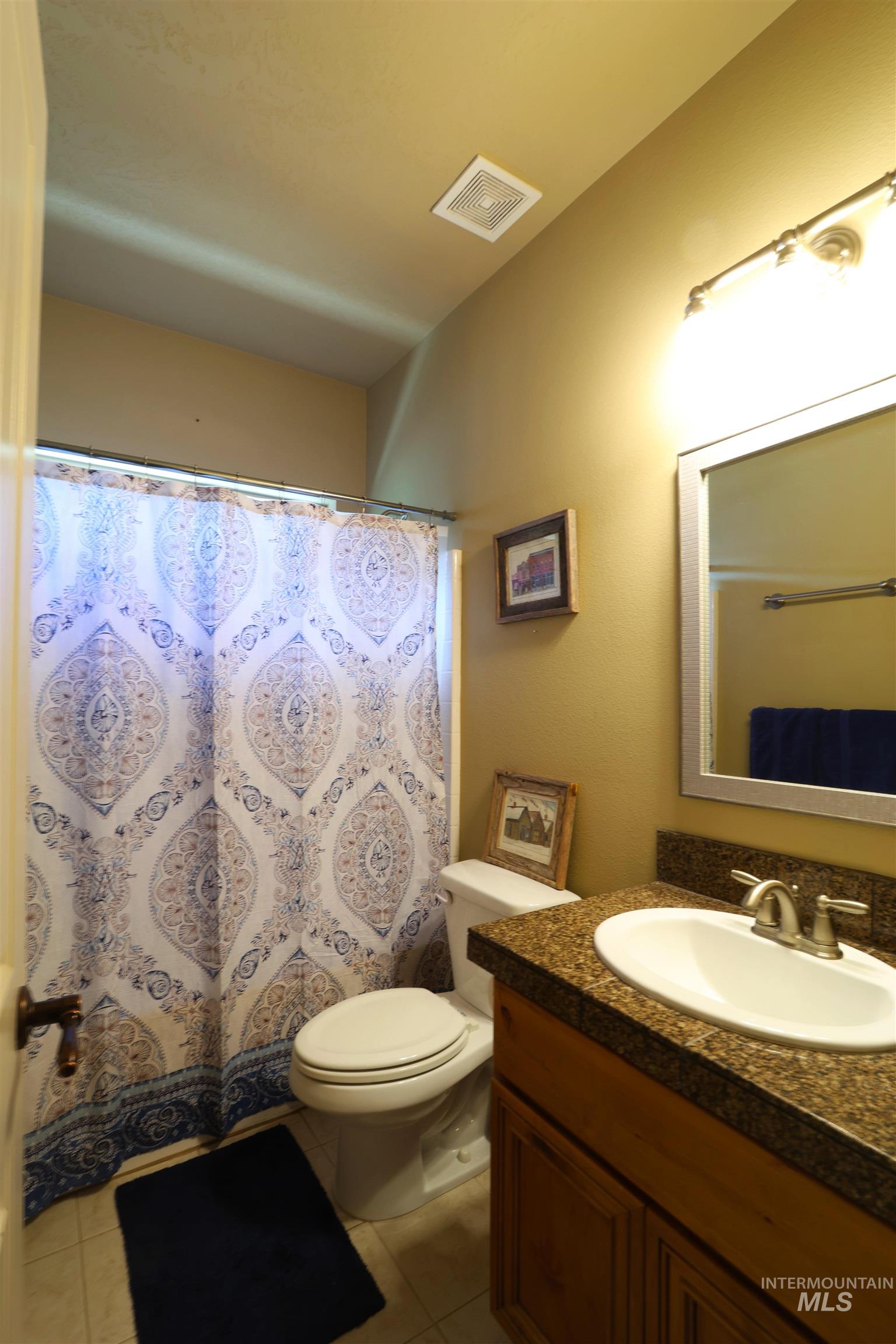 2278 Golf Lane Council, ID 83612 - Photo 17 of 31 Bathroom featuring a single vanity with an integrated sink and granite-style countertop, a wall-mounted mirror, and a toilet