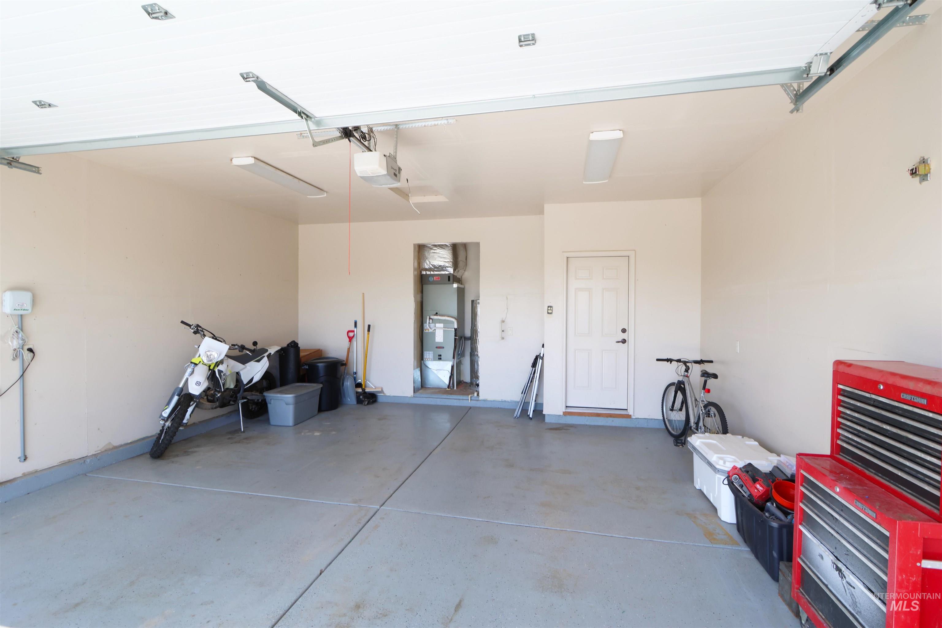 2278 Golf Lane Council, ID 83612 - Photo 22 of 31 Spacious garage featuring a concrete floor, overhead lighting, an automatic garage door opener, and a side entry door