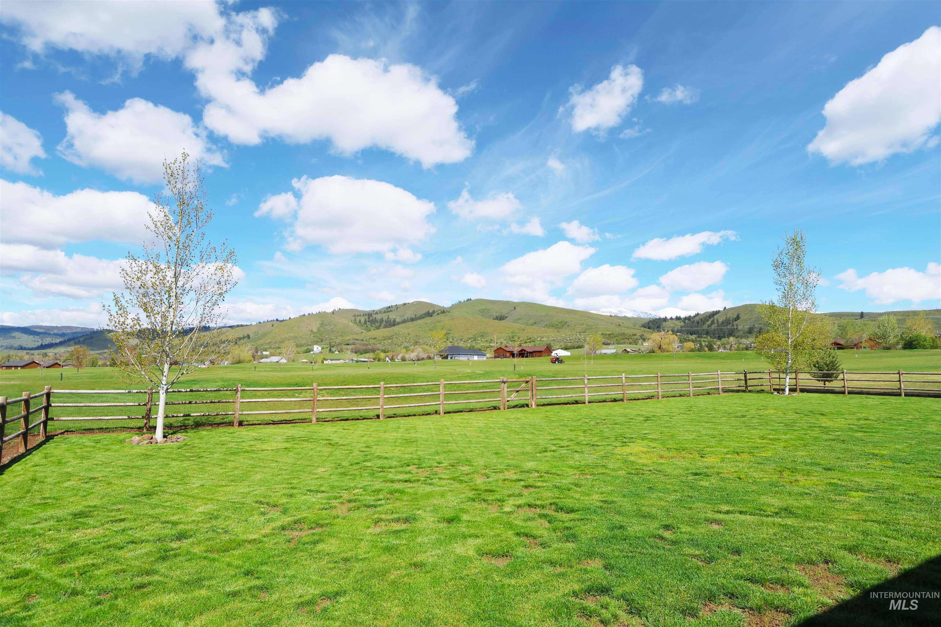 2278 Golf Lane Council, ID 83612 - Photo 26 of 31 Expansive green lawn with mountain backdrop, bordered by a split-rail fence