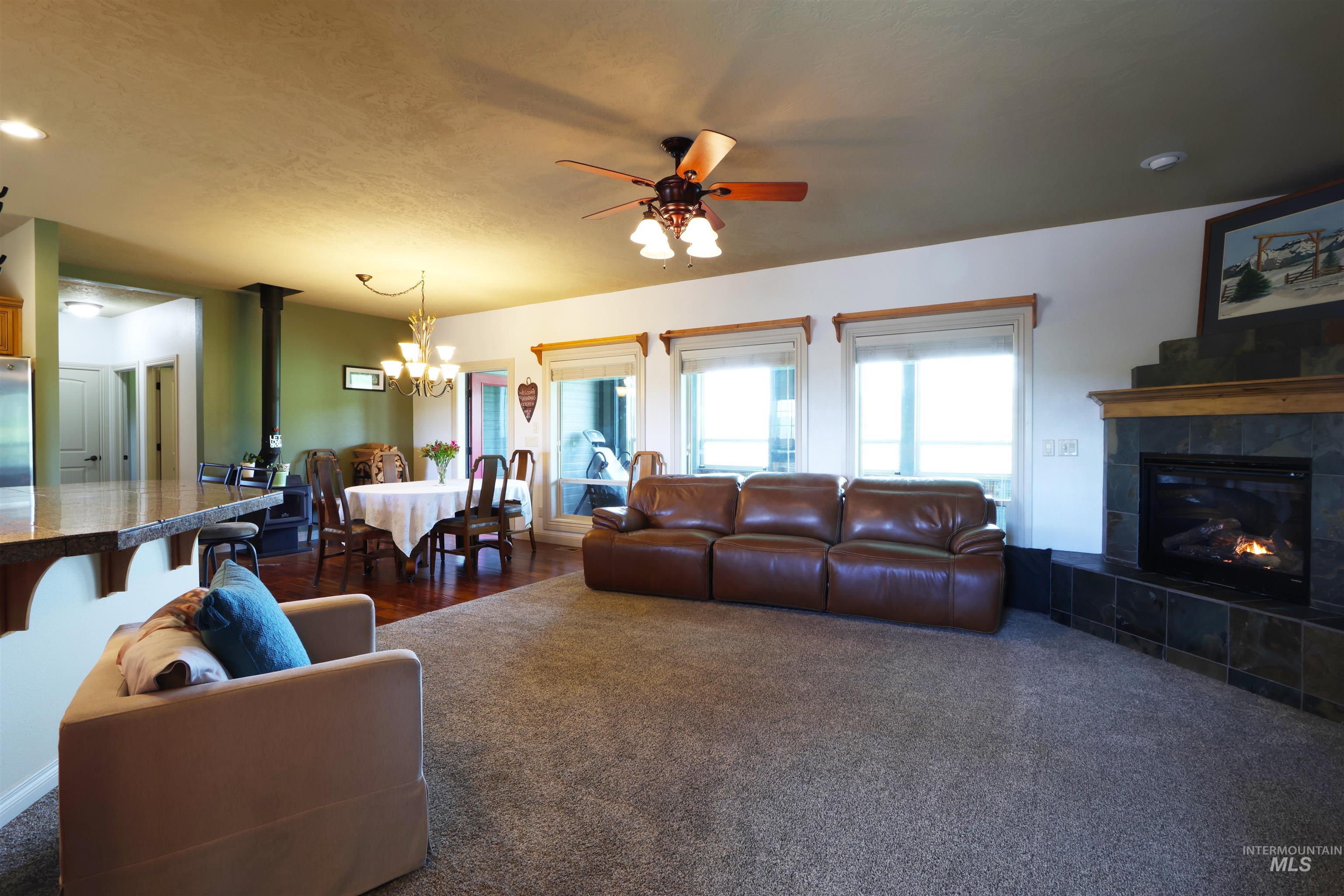 2278 Golf Lane Council, ID 83612 - Photo 3 of 31 Open-concept living space featuring a carpeted lounge area, a dining area with wood-finish flooring, and a breakfast bar