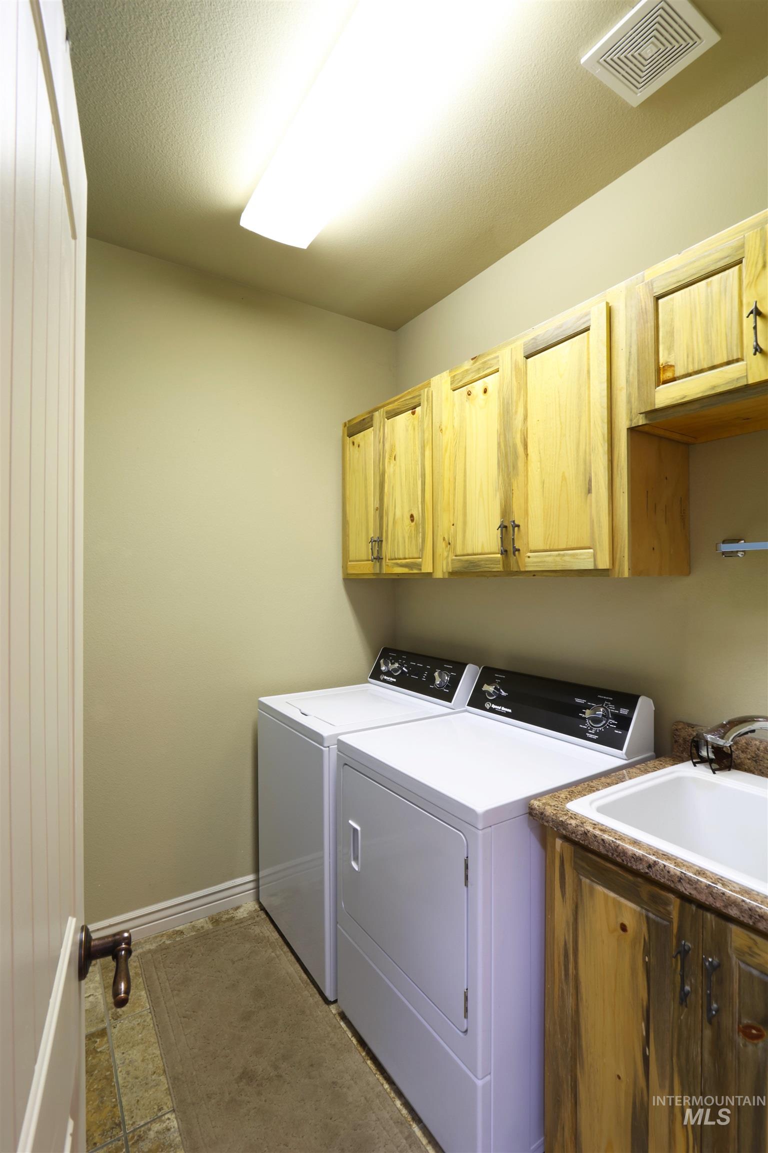 2278 Golf Lane Council, ID 83612 - Photo 9 of 31 Dedicated utility room featuring upper wood cabinetry, a built-in sink with a countertop, and durable tile flooring
