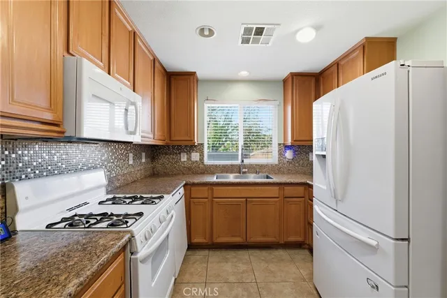 a kitchen with stainless steel appliances granite countertop a stove a refrigerator and a sink