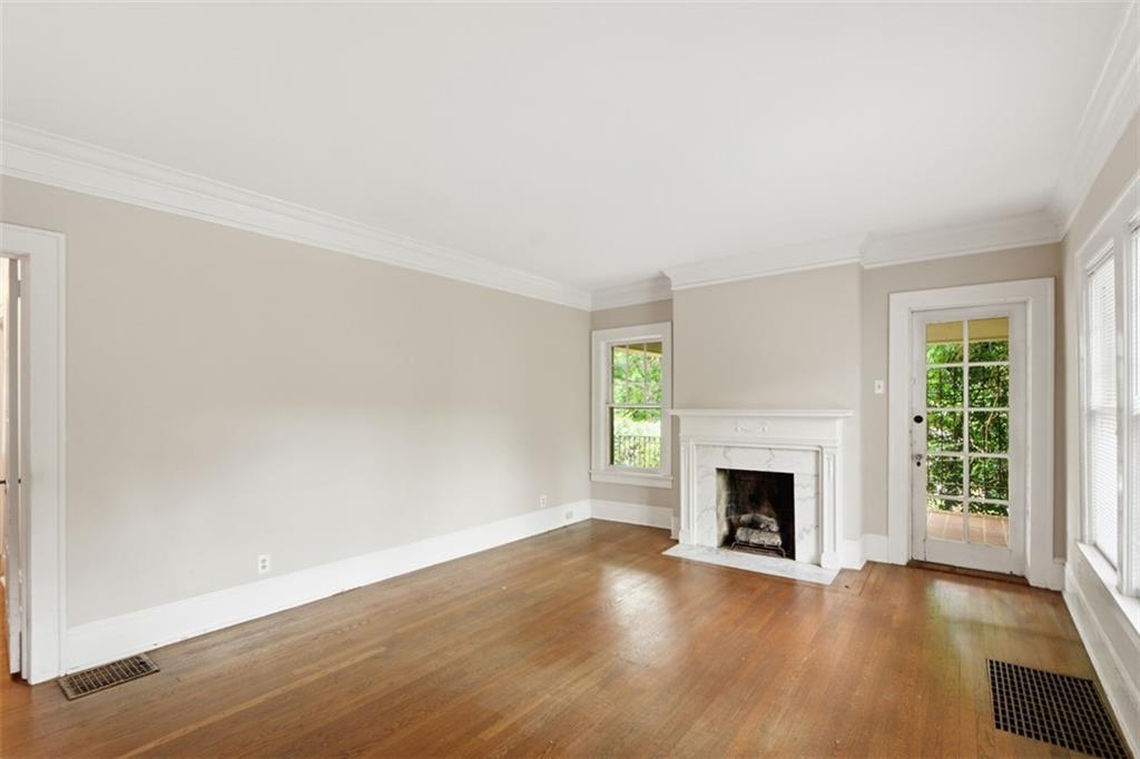 1424 Emory Road Northeast Atlanta, GA 30306 - Photo 6 of 36 an empty room with wooden floor fireplace and windows