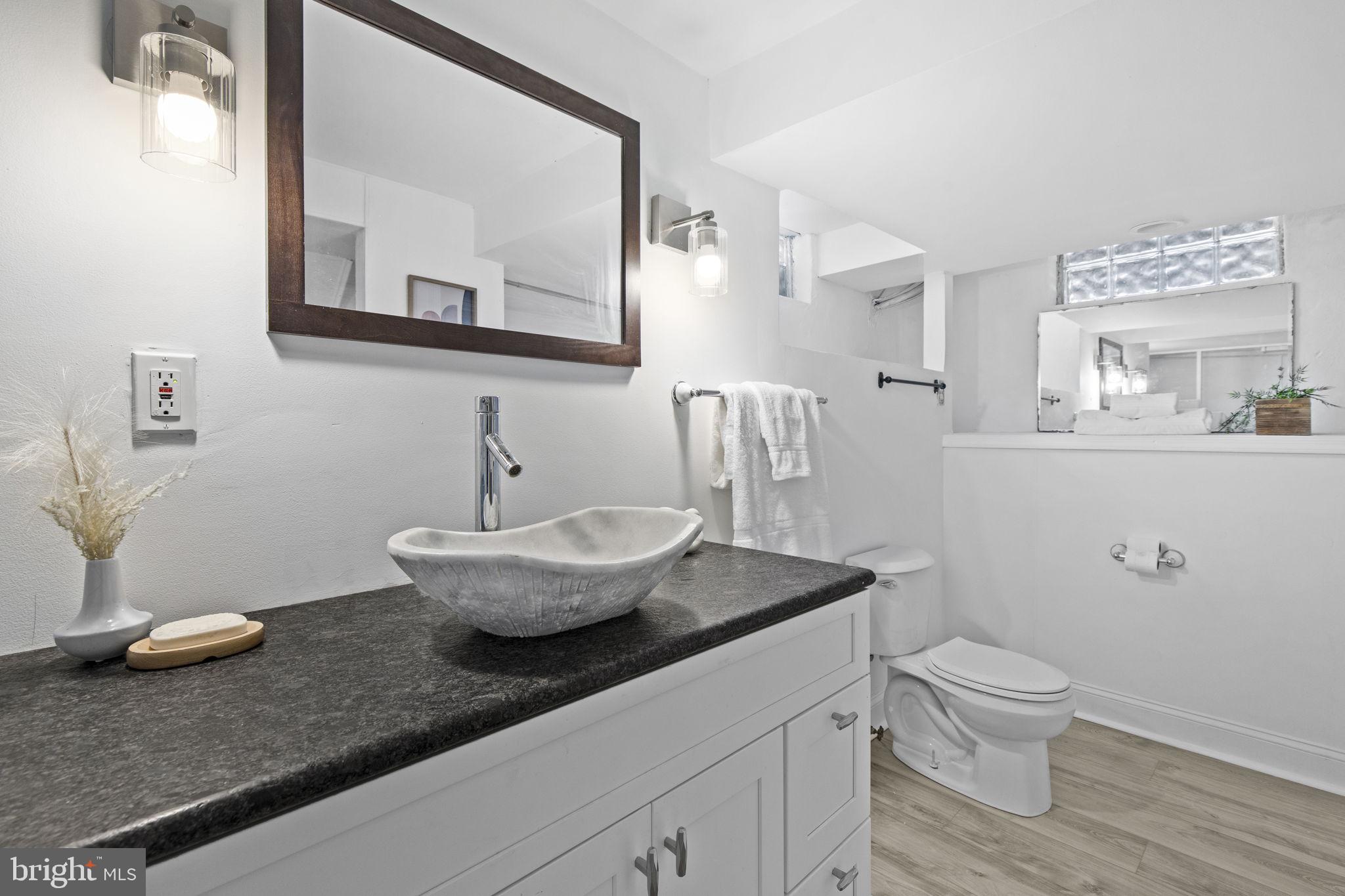 8105 Hillendale Road Baltimore, MD 21234 - Photo 29 of 39 a bathroom with a granite countertop toilet a sink and a mirror