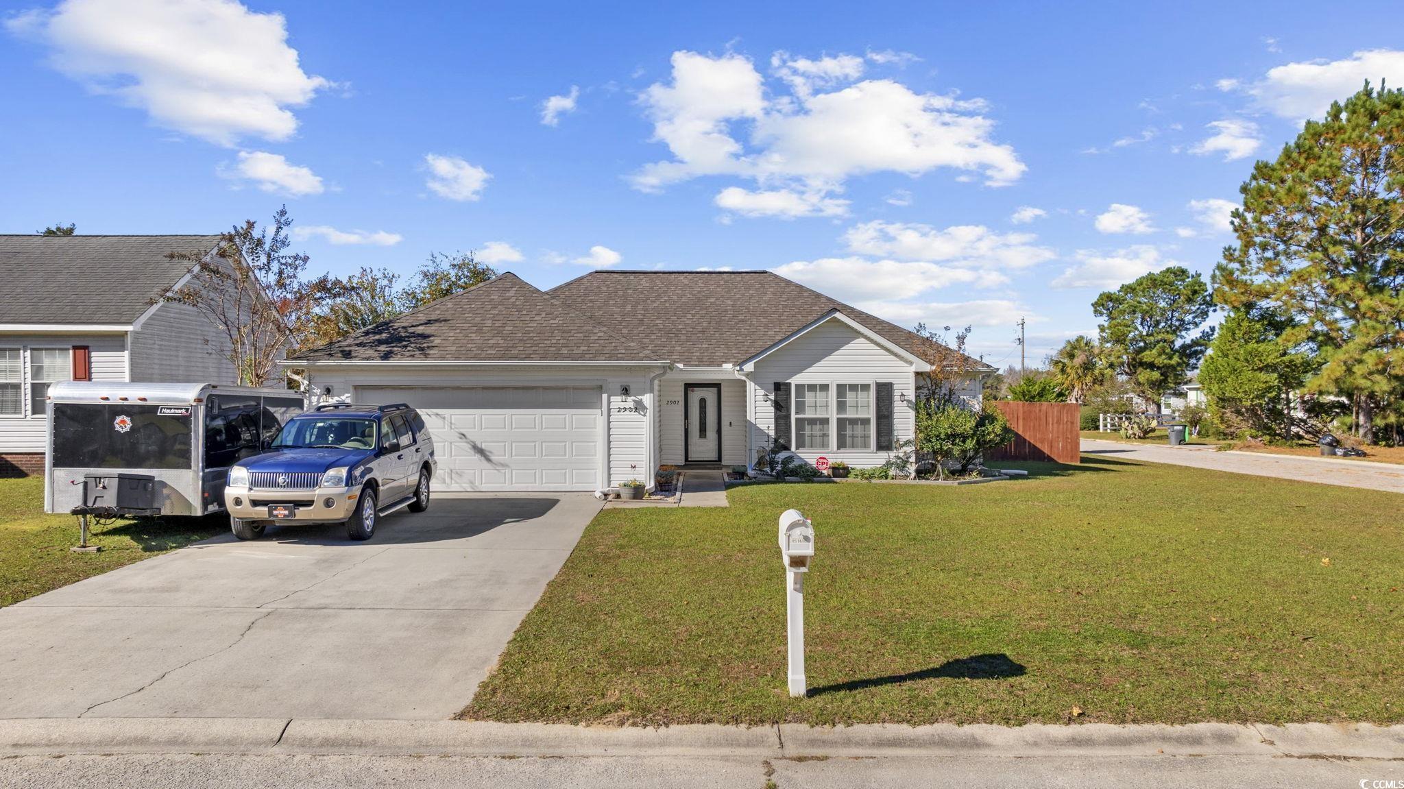Single story home featuring a front yard, roof with shingles, concrete driveway, and an attached garage