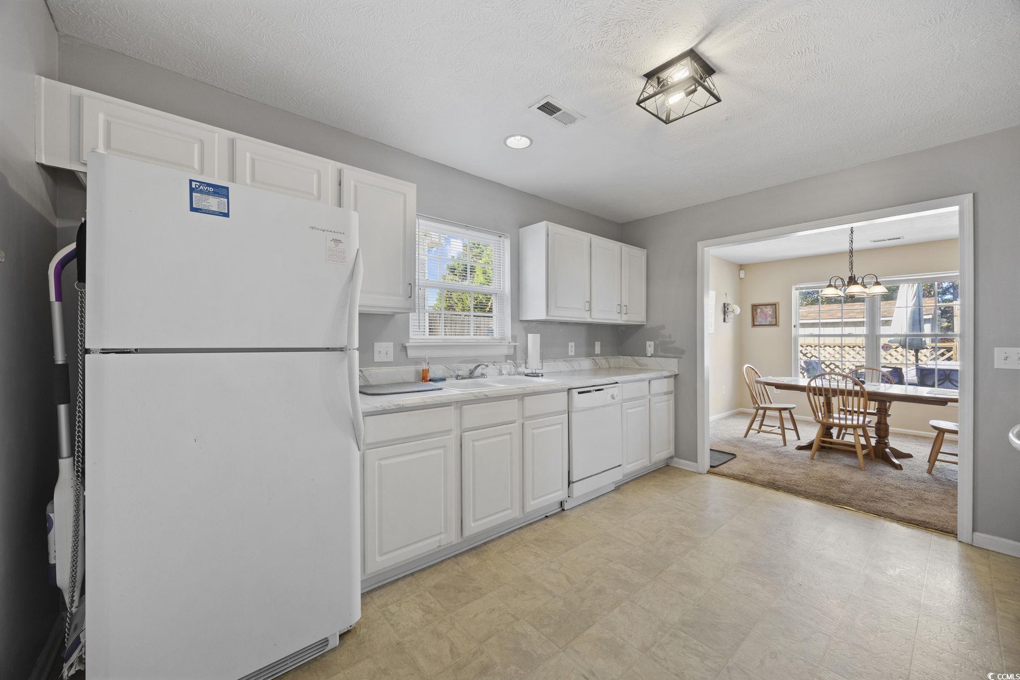 2902 Silverleaf Circle Loris, SC 29569 - Photo 11 of 38 Kitchen featuring white appliances, white cabinets, light countertops, light floors, and a chandelier