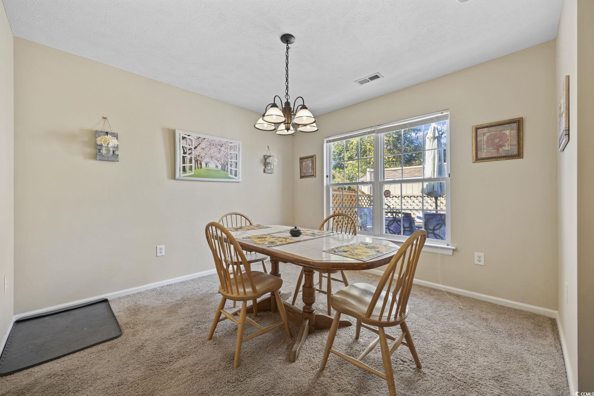 2902 Silverleaf Circle Loris, SC 29569 - Photo 7 of 38 Dining space with light colored carpet, a chandelier, and a textured ceiling