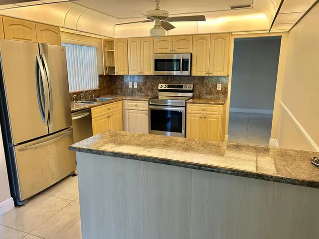 a kitchen with stainless steel appliances granite countertop a refrigerator a stove a sink and a microwave