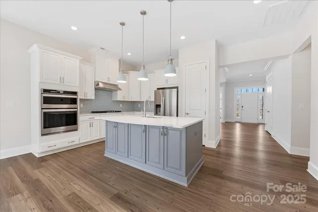 a kitchen with a white appliances cabinets and wooden floor