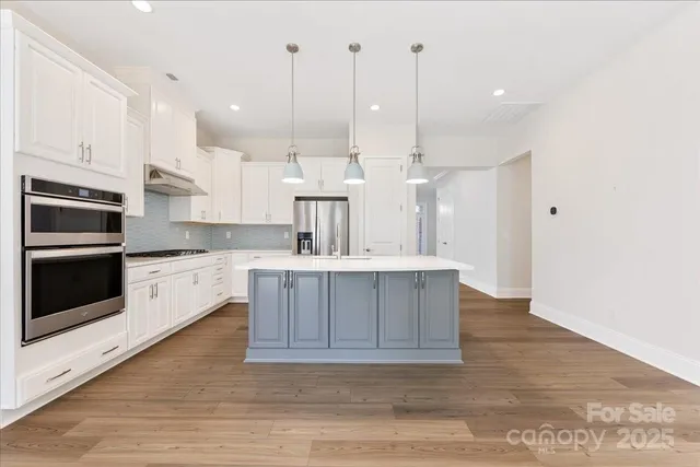 a large kitchen with kitchen island a sink stainless steel appliances and cabinets