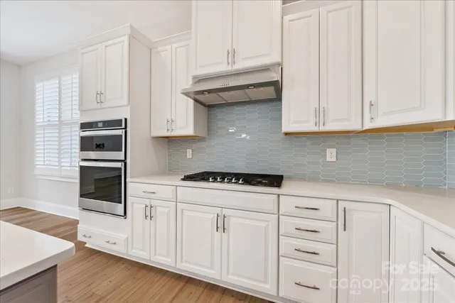 a kitchen with granite countertop white cabinets and stainless steel appliances