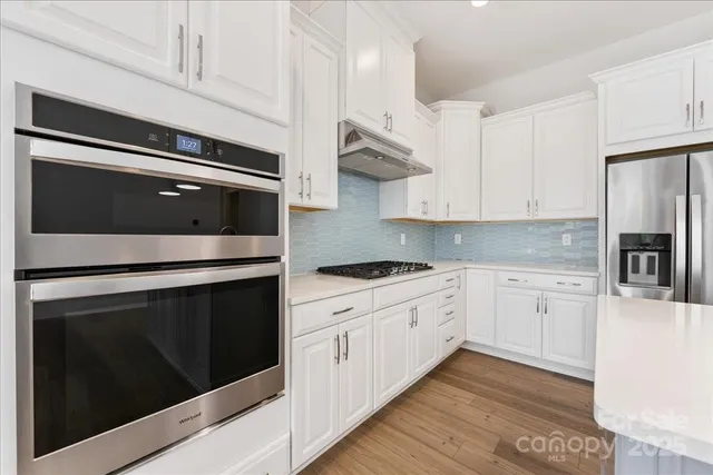 a kitchen with stainless steel appliances white cabinets and stove