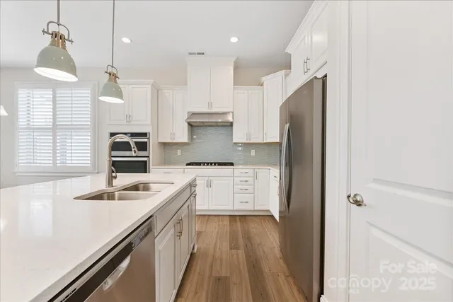 a kitchen with a refrigerator a sink and wooden floor