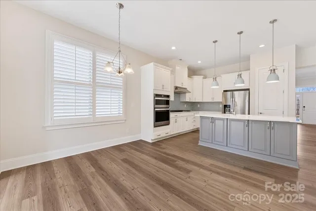 a view of kitchen with wooden floor window and cabinets