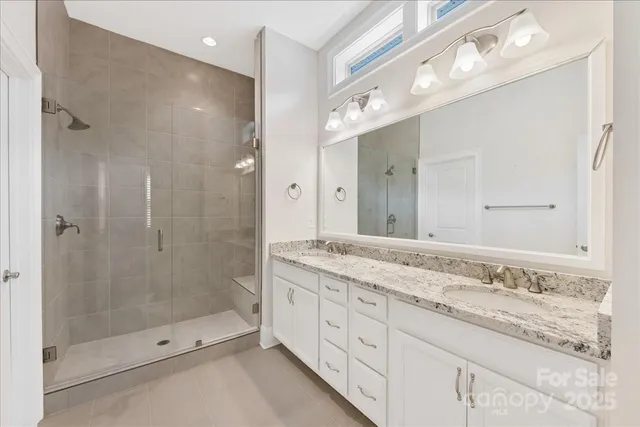 a bathroom with a granite countertop double vanity sink mirror double and shower