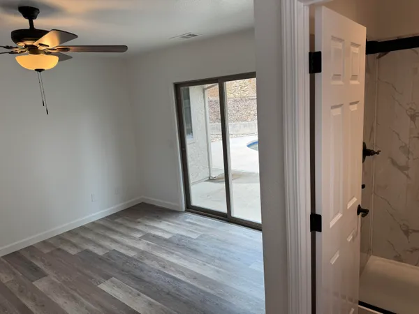 a view of an empty room with a window and wooden floor