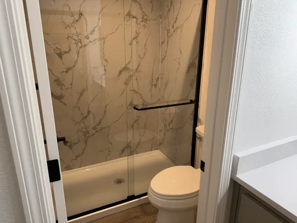 a bathroom with a granite countertop toilet and a shower