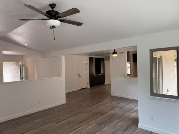 a view of an empty room with window and wooden floor