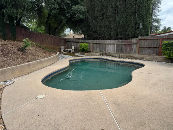 a view of a swimming pool with a patio and wooden fence