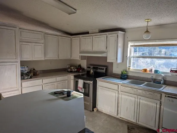 a kitchen with cabinets appliances a sink and a window