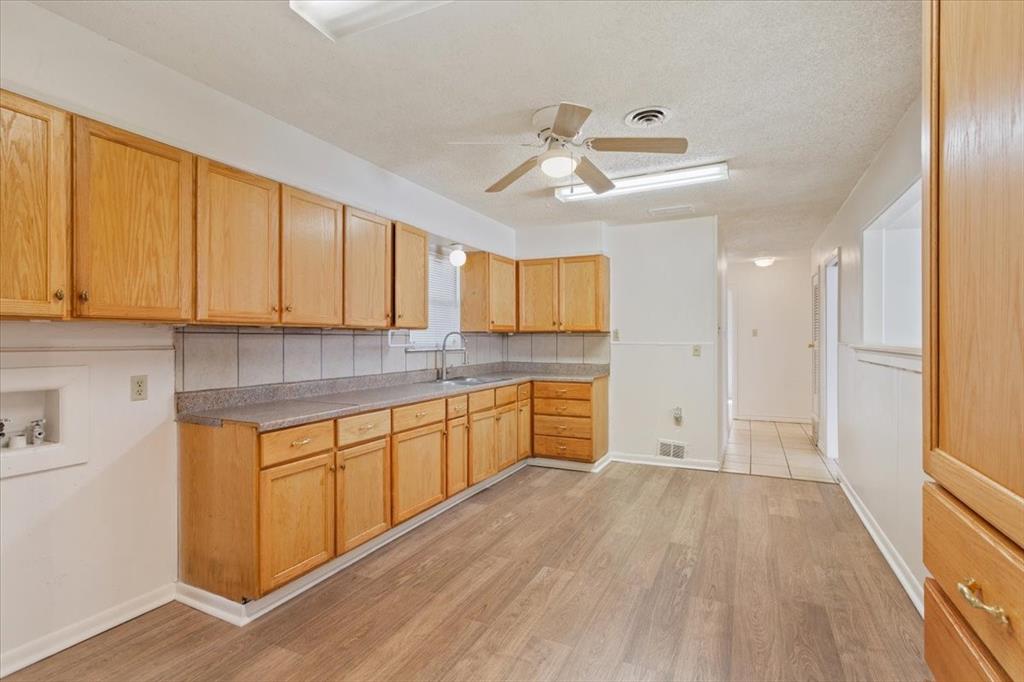 2424 South 26th Street Waco, TX 76706 - Photo 9 of 25 a kitchen with granite countertop wooden floors white cabinets and stainless steel appliances