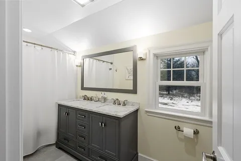 a bathroom with a granite countertop sink mirror and window