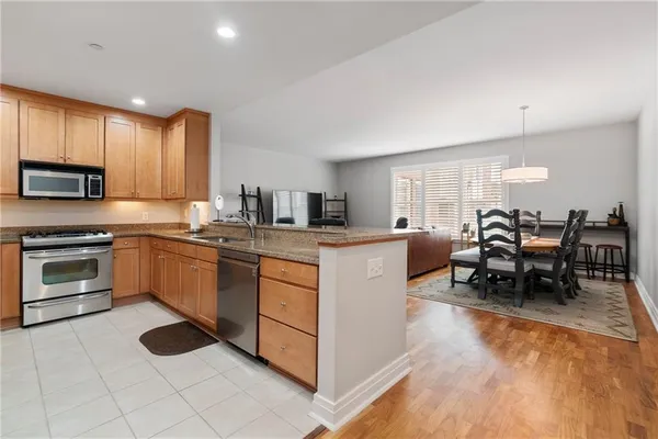 a kitchen with stainless steel appliances granite countertop a stove top oven a sink dishwasher and cabinets with wooden floor