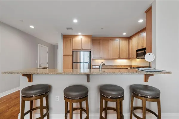 a kitchen with stainless steel appliances granite countertop a table chairs sink and cabinets