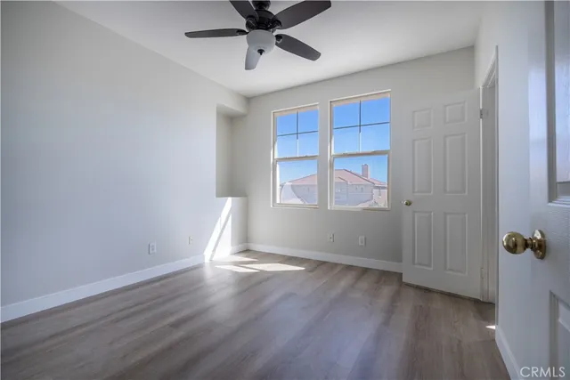 an empty room with wooden floor closet and windows