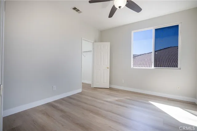 an empty room with a ceiling fan and wooden floor