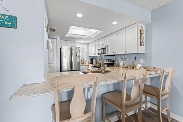 a kitchen with stainless steel appliances granite countertop a table chairs sink and cabinets