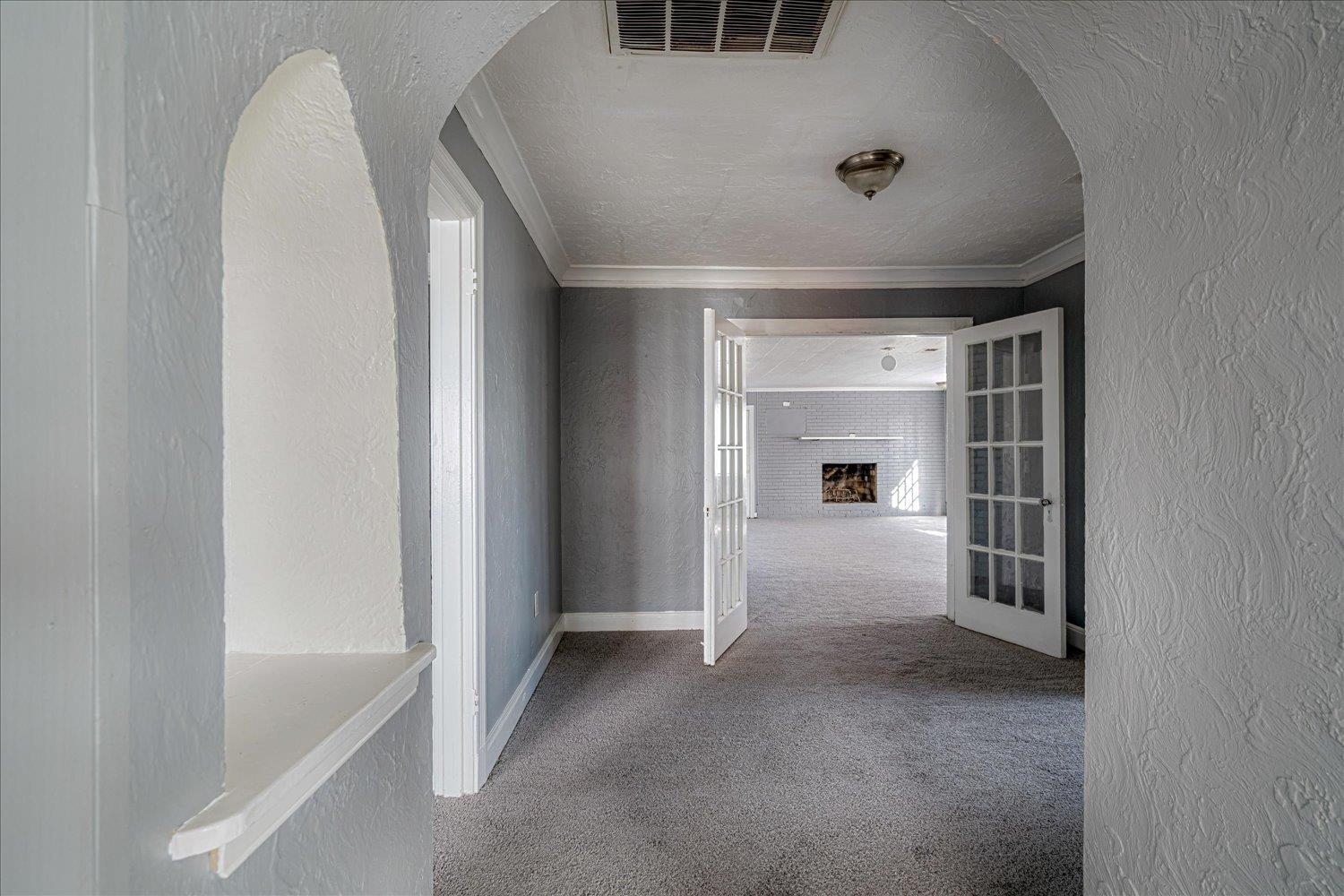 1114 Brownlee Road Memphis, TN 38116 - Photo 12 of 32 Corridor featuring a textured wall, carpet flooring, french doors, arched walkways, and ornamental molding