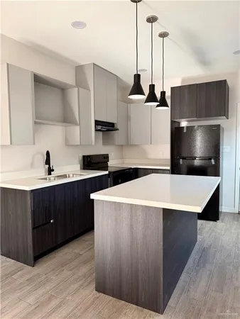 a kitchen with stainless steel appliances a stove a refrigerator a sink and white cabinets