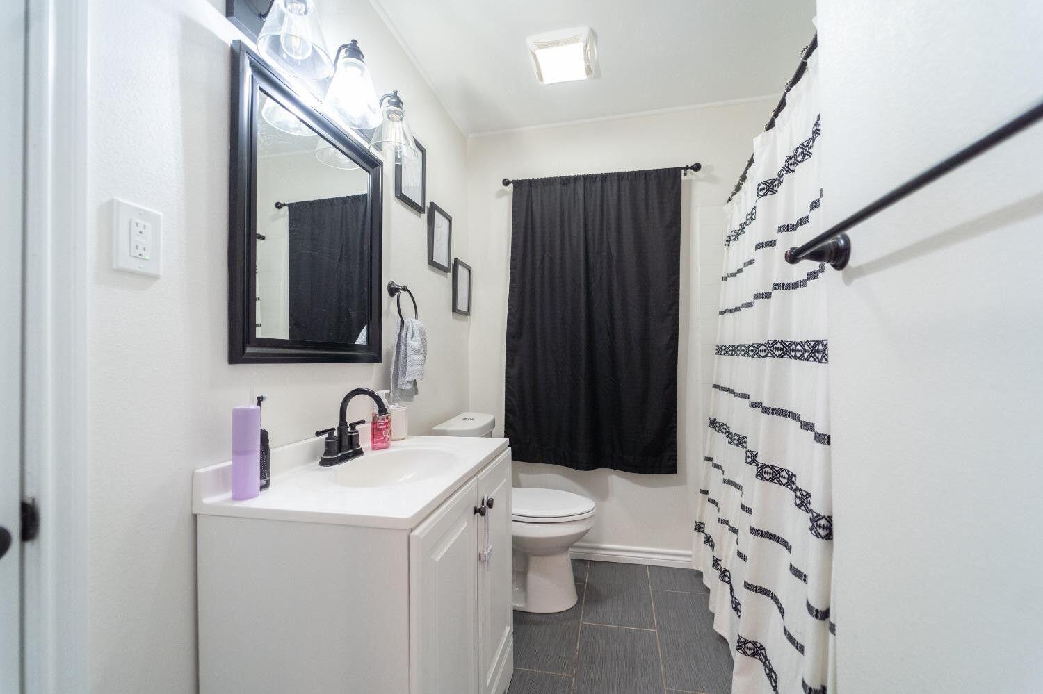1517 41st Street Lubbock, TX 79412 - Photo 12 of 22 a bathroom with a sink toilet vanity and shower