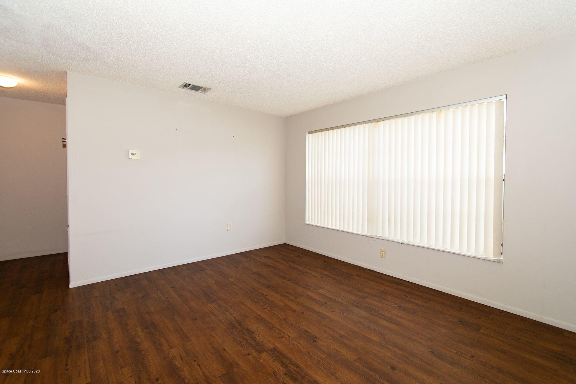 2872 Pembroke Road Melbourne, FL 32935 - Photo 5 of 32 an empty room with wooden floor and windows