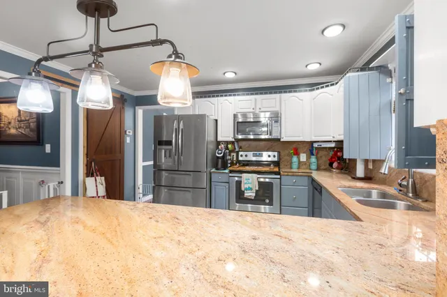 a kitchen with stainless steel appliances kitchen island granite countertop a refrigerator oven a sink dishwasher and couches with wooden floor