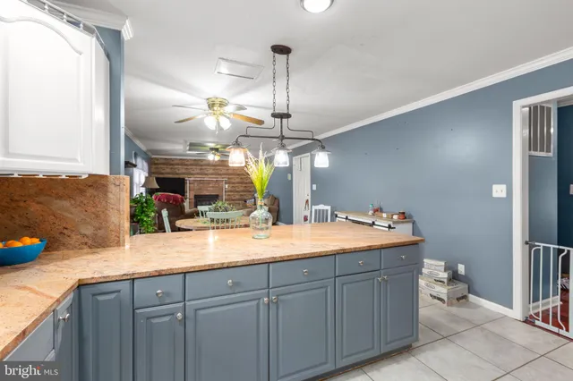 a dining hall with stainless steel appliances granite countertop a sink dishwasher and a fireplace with wooden floor