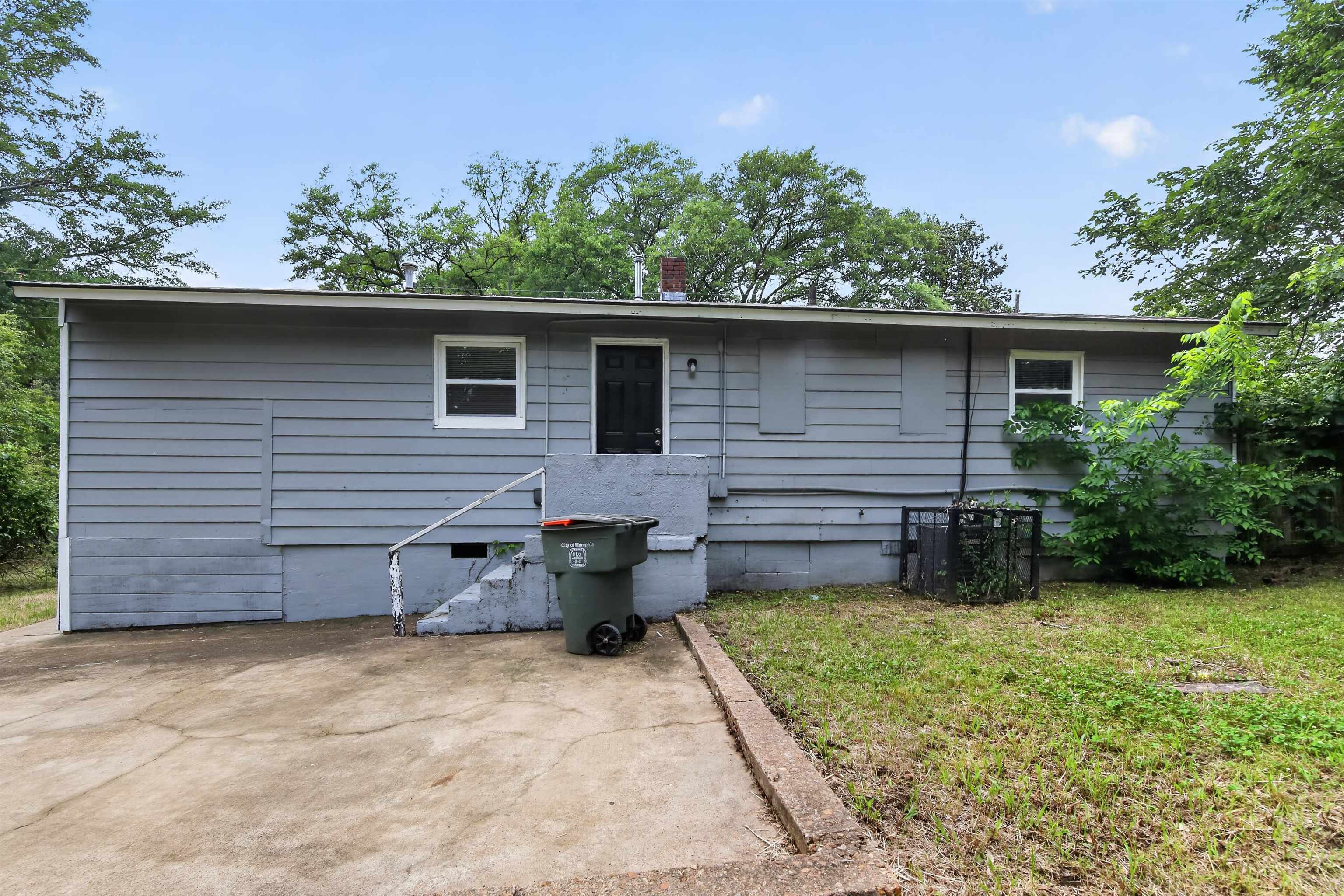 4838 Manson Road Memphis, TN 38109 - Photo 6 of 28 Single-story residence featuring light gray horizontal siding, a dark entry door, and white-framed windows