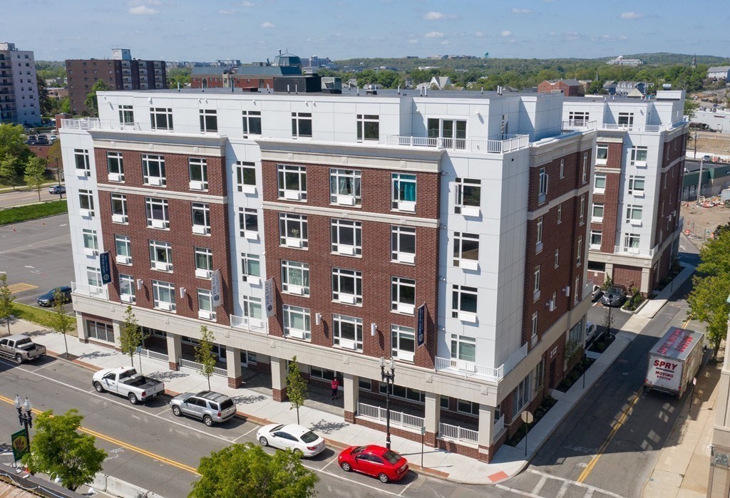 a front view of a building with glass windows and cars