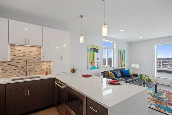 a kitchen with a sink dishwasher a stove and white cabinets with wooden floor