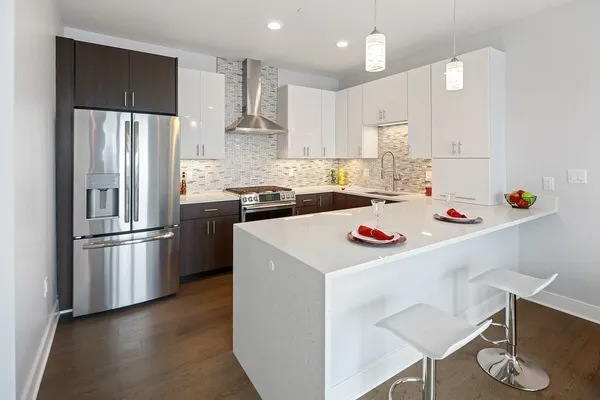 a kitchen with a refrigerator a stove a sink and white cabinets with wooden floor