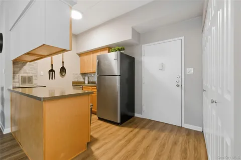 a view of a kitchen with refrigerator and wooden floor