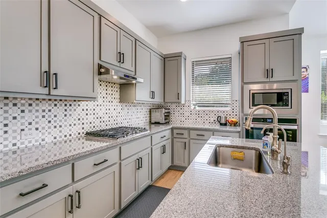 a kitchen with stainless steel appliances granite countertop a sink stove and cabinets